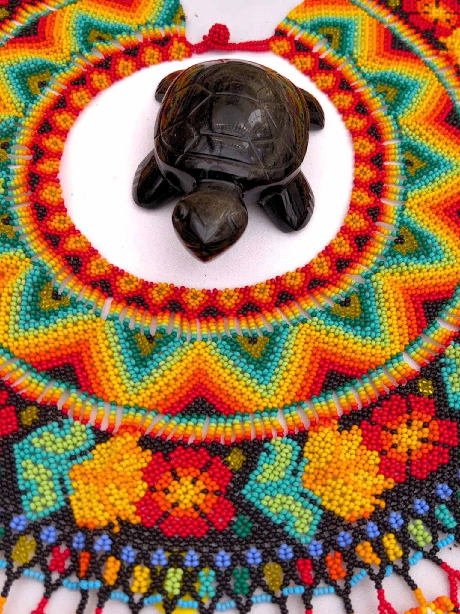 Hand-carved turtle sculpture displayed on vibrant Indigenous beadwork, representing sacred artistry, ancestral symbolism, and handcrafted cultural expression within Collective Journey Art.