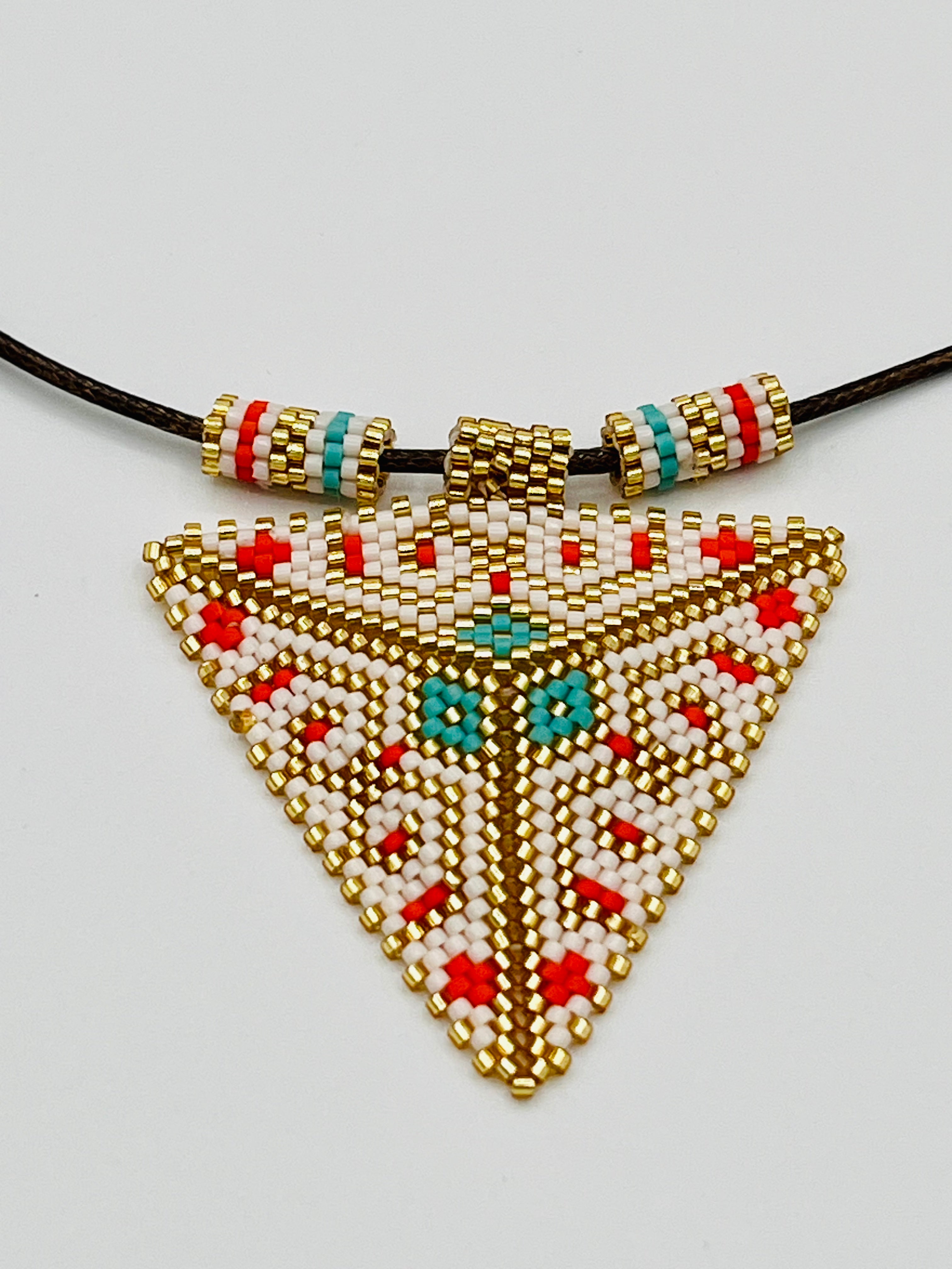 Close-up of the Pyramid of Third Eye beaded pendant — a handwoven sacred talisman crafted by T’zutujil artisans in Guatemala using rare Miyuki beads. Featuring gold, turquoise, red, and white patterns inspired by tribal symbology, the piece represents heart, mind, and soul alignment.