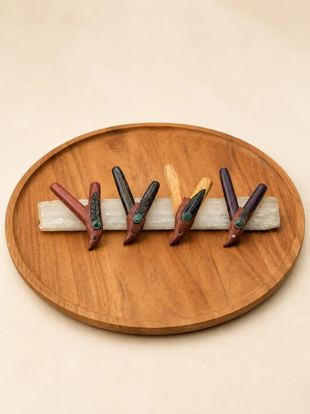Four handcrafted Bird Kuripe Hapé self-applicators in varied natural woods, arranged on a white stone slab over a round wooden tray