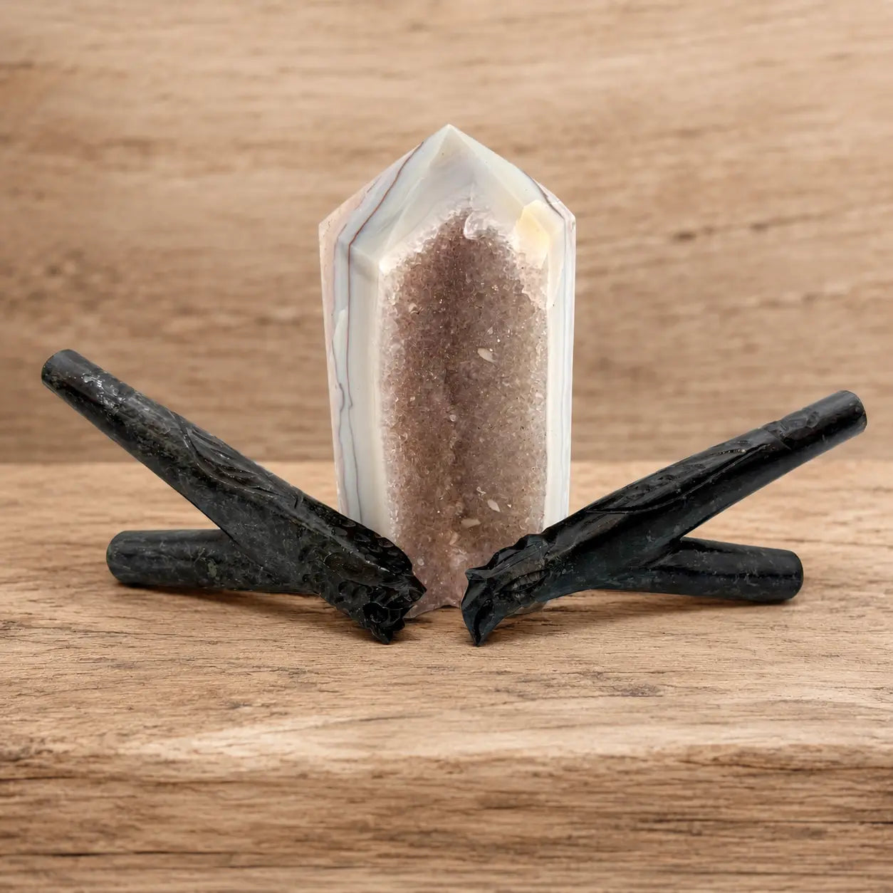 Two handcrafted Black Serpentine Kuripes by Collective Journey Art, designed for self-applying Hapé, arranged on a light wooden surface beside a natural agate crystal tower.